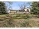 Backyard view with a multi-tiered retaining wall, grass lawn, and the rear exterior of the home at 8898 W Harvard Pl, Lakewood, CO 80227