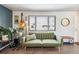Bright living room with wood floors, a plush green sofa, and a large window offering pleasant views at 8898 W Harvard Pl, Lakewood, CO 80227