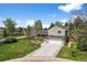 Attractive two-story home with a well-kept lawn, mature trees, and a long driveway leading to the garage at 10743 W Turtle Mtn, Littleton, CO 80127