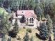 View of cabin-style home with red roof nestled in a lush forest setting at 28650 Cavan Ln, Evergreen, CO 80439