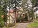 Charming exterior view of a home with a red roof, surrounded by lush trees and a paved driveway at 28650 Cavan Ln, Evergreen, CO 80439