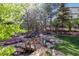 Beautiful backyard pond with waterfall, bridge, and hot tub, surrounded by mature trees and landscaping at 9188 Buck Hill Dr, Highlands Ranch, CO 80126