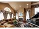 A living room with a fireplace, piano, large arched window, and comfortable furnishings at 9188 Buck Hill Dr, Highlands Ranch, CO 80126