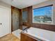 Bright bathroom featuring a soaking tub and glass-enclosed shower, enhanced by natural light from a large window at 342 Olympia Ave, Longmont, CO 80504