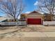 Detached two-car garage featuring a striking red door and a charming white picket fence, adding to the curb appeal at 342 Olympia Ave, Longmont, CO 80504
