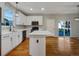 Well-lit kitchen boasting white cabinetry, stainless steel appliances, a center island, and beautiful hardwood flooring at 342 Olympia Ave, Longmont, CO 80504