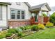 Charming home exterior with brick accents, a covered porch, lush landscaping, and a well-manicured lawn at 8267 S Sicily Ct, Aurora, CO 80016