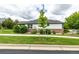 Well-maintained home featuring brick accents, lush landscaping, and a pristine lawn viewed from across the street at 8267 S Sicily Ct, Aurora, CO 80016