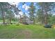 Expansive backyard featuring a fire pit, seating, and a swing set, surrounded by mature trees at 4724 Hopi Rd, Indian Hills, CO 80454