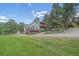 Exterior elevation of a home with a garage, two decks, mature landscaping and a long driveway at 4724 Hopi Rd, Indian Hills, CO 80454