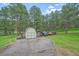 Exterior view of a shed and parking area on a property with mature trees and green space at 4724 Hopi Rd, Indian Hills, CO 80454