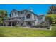 Back of a beautiful gray house, featuring two decks with stairs leading down to a lush green lawn at 5542 Ponderosa Dr, Parker, CO 80134