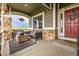 Inviting front porch featuring stone pillars, comfortable seating, a wood table, and a red front door at 28495 La Donna Vista Ln, Elizabeth, CO 80107