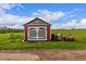 A quaint red shed with gray doors, alongside a tractor and lawnmower in a lush field at 28495 La Donna Vista Ln, Elizabeth, CO 80107