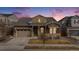 Charming home exterior featuring stone accents, covered porch, and well-maintained landscaping during twilight hours at 10114 Atlanta St, Parker, CO 80134