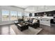Open-concept living room with dark hardwood floors, large windows, and a comfortable leather sectional sofa at 10114 Atlanta St, Parker, CO 80134