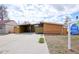 Modern home featuring wooden siding, a carport, and a well-kept concrete driveway with lush green foliage at 5350 E 66Th Way, Commerce City, CO 80022