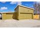 Spacious yellow detached garage with two bays and a basketball hoop against a bright blue sky at 5350 E 66Th Way, Commerce City, CO 80022