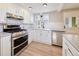 Bright kitchen featuring white cabinets, stainless steel appliances, modern light fixtures, and new floors at 5350 E 66Th Way, Commerce City, CO 80022
