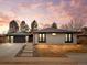 Charming single story brick home features a modern garage, pathway and manicured front yard under a colorful sky at 3049 S Vine St, Denver, CO 80210