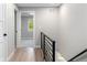 Hallway featuring hardwood floors, a modern metal railing, and an open doorway to a bedroom at 1660 S Kingston Way, Aurora, CO 80012