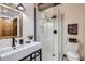 Bathroom with modern white vanity, a glass-enclosed shower, and a toilet with wall art at 10439 Christopher Dr, Conifer, CO 80433