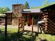 Charming log home with stone chimney and welcoming gated entrance, surrounded by lush greenery at 10439 Christopher Dr, Conifer, CO 80433