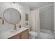 Bright bathroom featuring modern fixtures, gold accents, a round mirror, and a shower-tub with a neutral curtain at 5250 Cody St, Arvada, CO 80002