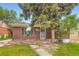 Cozy brick home featuring a mature tree in the front yard and a vintage brick porch at 4624 W Virginia Ave, Denver, CO 80219
