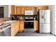 Eat-in kitchen featuring stainless steel appliances, wooden cabinets and dark tile backsplash at 9852 E Idaho St, Aurora, CO 80247