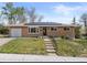 Charming brick home with a well-manicured lawn and solar panels installed on the roof at 4102 W Eastman Ave, Denver, CO 80236