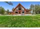 Charming log cabin featuring a wall of windows and an inviting outdoor seating area at 16861 Wrangler Trl, Littleton, CO 80127