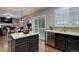 An open kitchen showcases a breakfast bar, stainless steel appliances, dark cabinets, and lots of natural light at 15372 E 117Th Ave, Commerce City, CO 80022