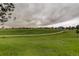 View of large grassy park in neighborhood with paved trail, playground and cloudy skies at 15372 E 117Th Ave, Commerce City, CO 80022