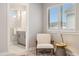 Bright bedroom showcases an accent chair and a window with an adjacent view into the bathroom at 6334 N Dayton Way, Denver, CO 80238