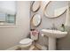 Charming powder room with pedestal sink, round mirrors, and natural light at 6334 N Dayton Way, Denver, CO 80238