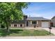 Inviting home exterior with lush trees, brick accents, a well-manicured lawn, and an attached garage at 4502 S Gar Way, Littleton, CO 80123