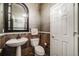 Stylish half bathroom featuring a pedestal sink, decorative mirror, and tiled wainscoting at 1221 Havenwood Way, Castle Pines, CO 80108