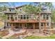 Exterior of home featuring back deck, walkout basement, stone patio, and mature trees at 1221 Havenwood Way, Castle Pines, CO 80108