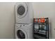 Stacked white washer and dryer next to shelving with laundry supplies at 8335 Fairmount Dr # 2-105, Denver, CO 80247
