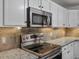 Close-up of kitchen featuring stainless steel microwave and cooktop with granite countertops at 7131 S Wenatchee Way # C, Aurora, CO 80016