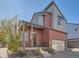 Inviting two-story home with red siding, well-kept landscaping, covered porch, and attached garage at 2514 Sweet Wind Ave, Castle Rock, CO 80109
