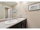 Bathroom with double sinks, dark cabinets, large mirror, and neutral walls offer a clean aesthetic at 15507 Quince Cir, Thornton, CO 80602
