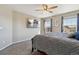 Inviting bedroom with a large TV, soft carpet, and two bright windows showcasing outside views at 15507 Quince Cir, Thornton, CO 80602