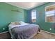Well-lit bedroom boasting bright windows, a cozy bed, and a tranquil green accent wall at 15507 Quince Cir, Thornton, CO 80602