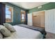Bright bedroom featuring a large window, closet, plush bedding, and calming green walls at 15507 Quince Cir, Thornton, CO 80602