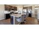 Modern kitchen with an island, breakfast bar, dark cabinets, and a stainless steel dishwasher at 15507 Quince Cir, Thornton, CO 80602