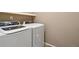 Modern laundry room with a white washer and dryer set and overhead shelf for storage at 15507 Quince Cir, Thornton, CO 80602