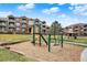 Community playground with a slide, greenery, and benches for parents at 7440 S Blackhawk St # 16-208, Englewood, CO 80112