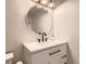 Updated bathroom features a vanity with modern fixtures, round mirror, and updated lighting at 2531 S Hoyt Ct, Lakewood, CO 80227